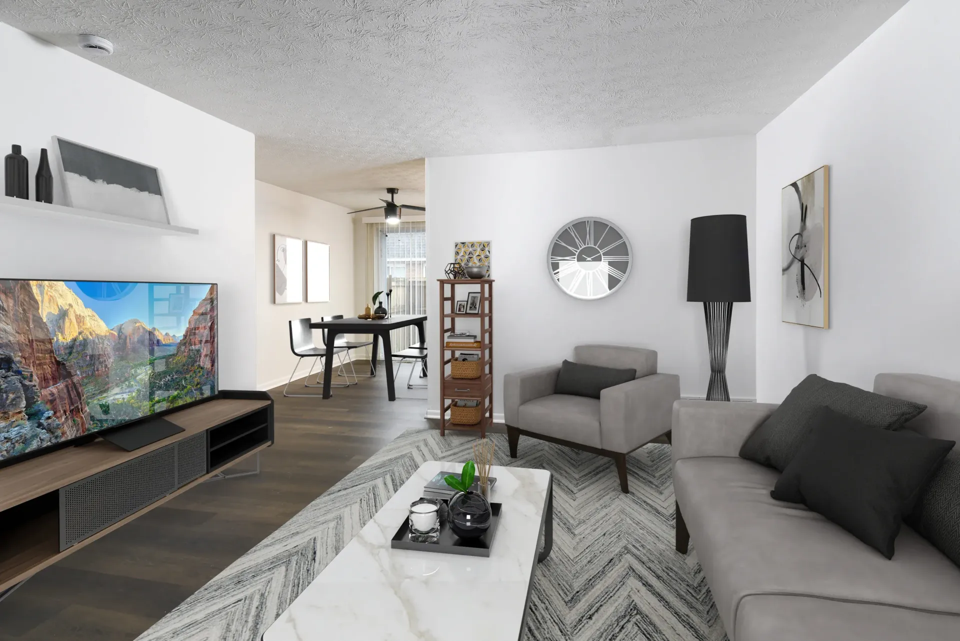 Modern apartment living room with gray sofa, coffee table, TV, and dining area.