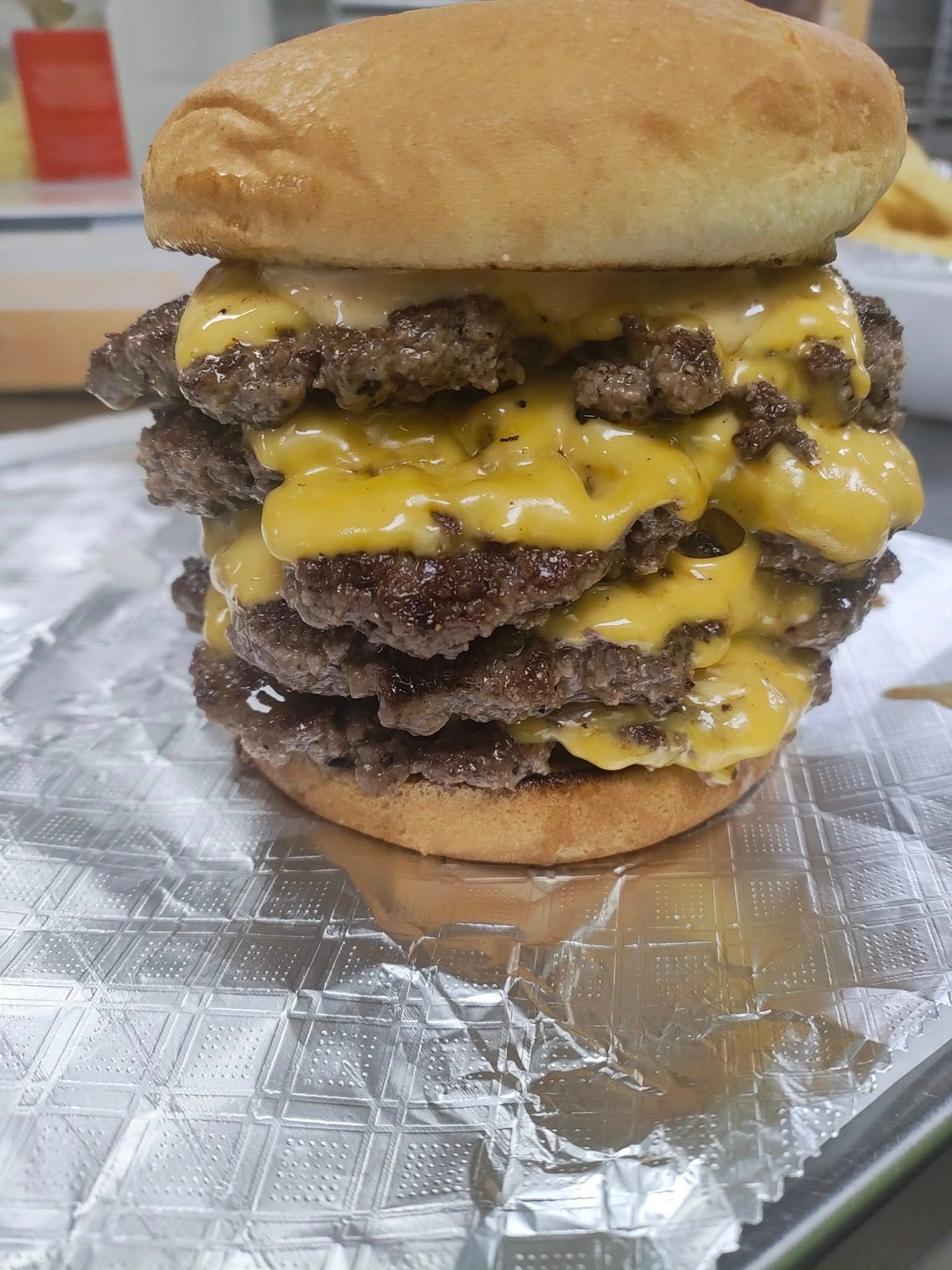 Stacked cheeseburger with five patties, melted yellow cheese, and a bun.