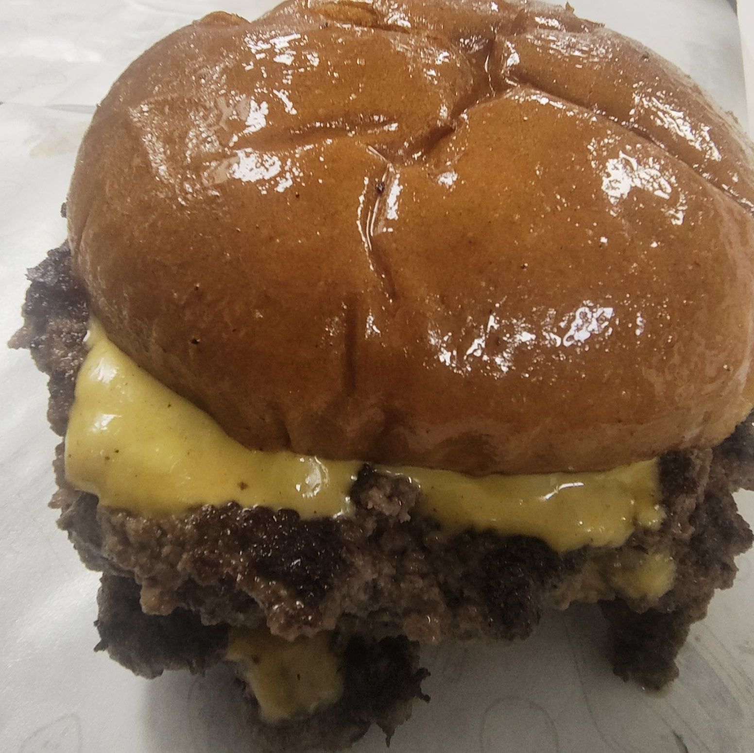 Cheeseburger with two patties, melted yellow cheese, and glossy brown bun.