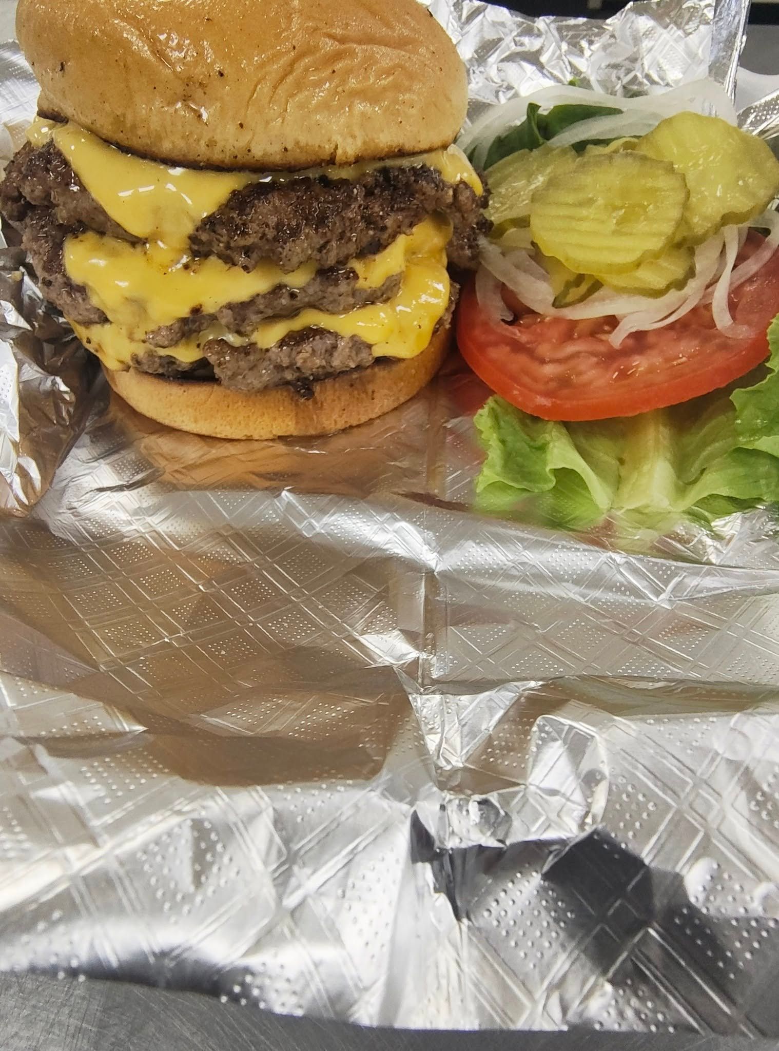 Double cheeseburger with toppings on foil.