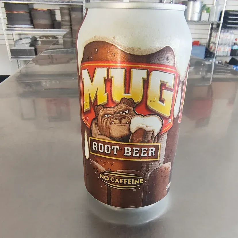 Mug Root Beer can with bulldog mascot on a metal counter.