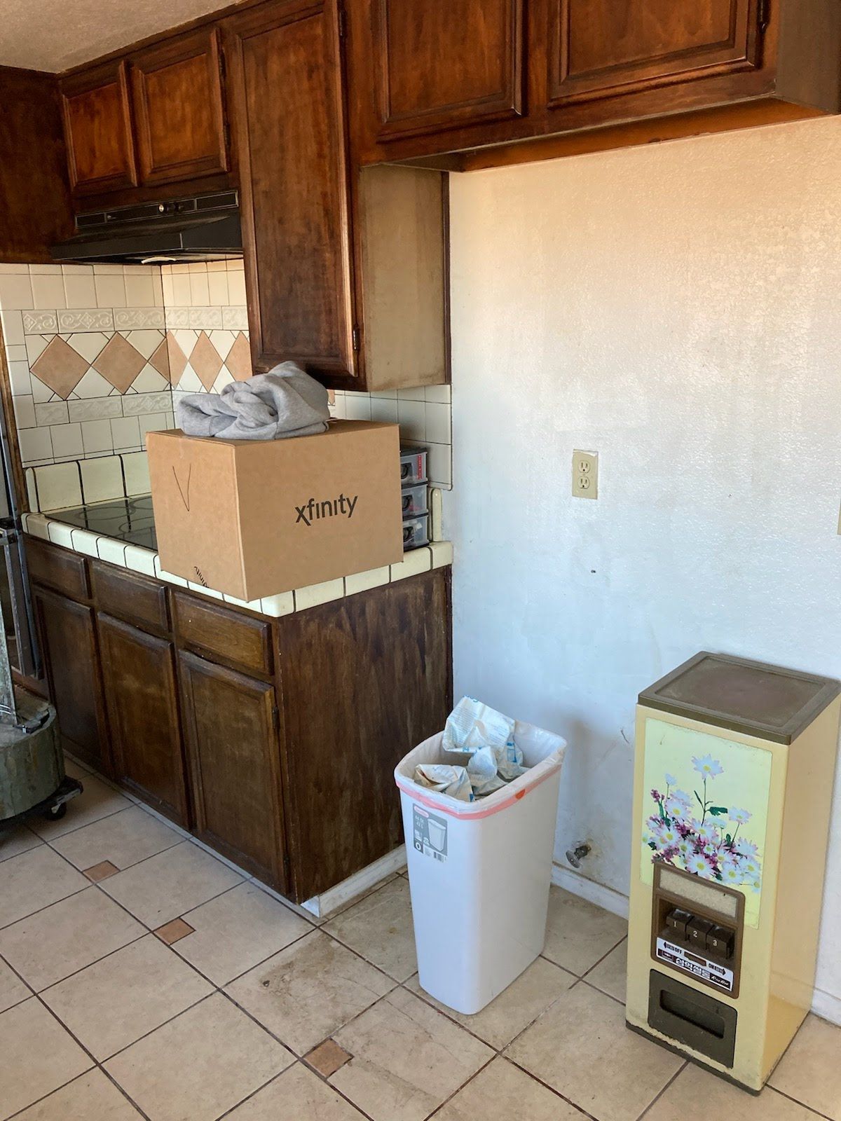 A kitchen with a trash can and a box on the counter