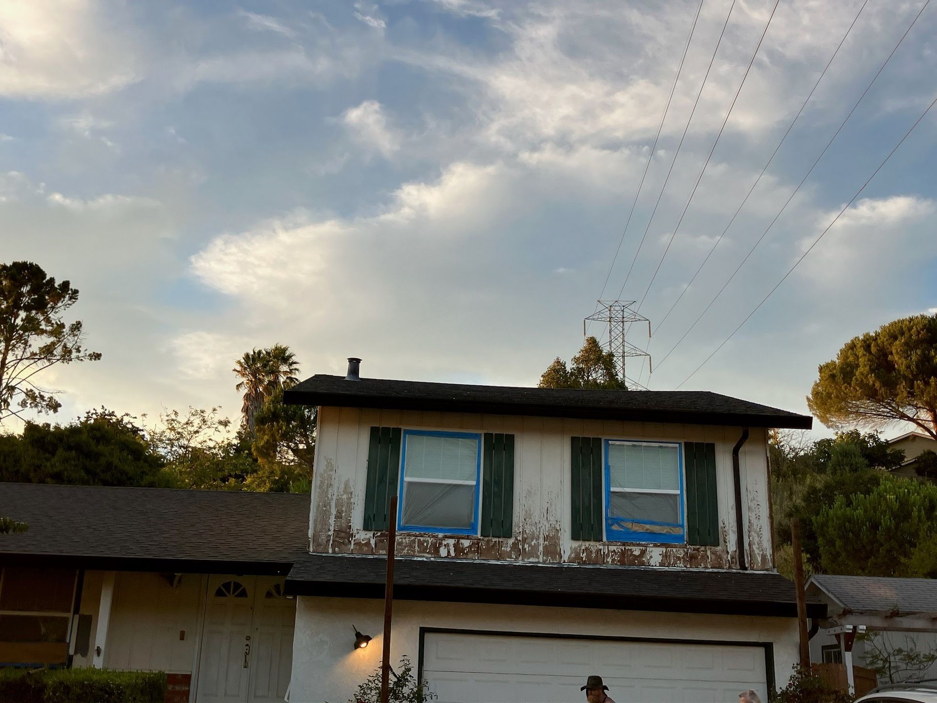 A white house with green shutters and a black roof