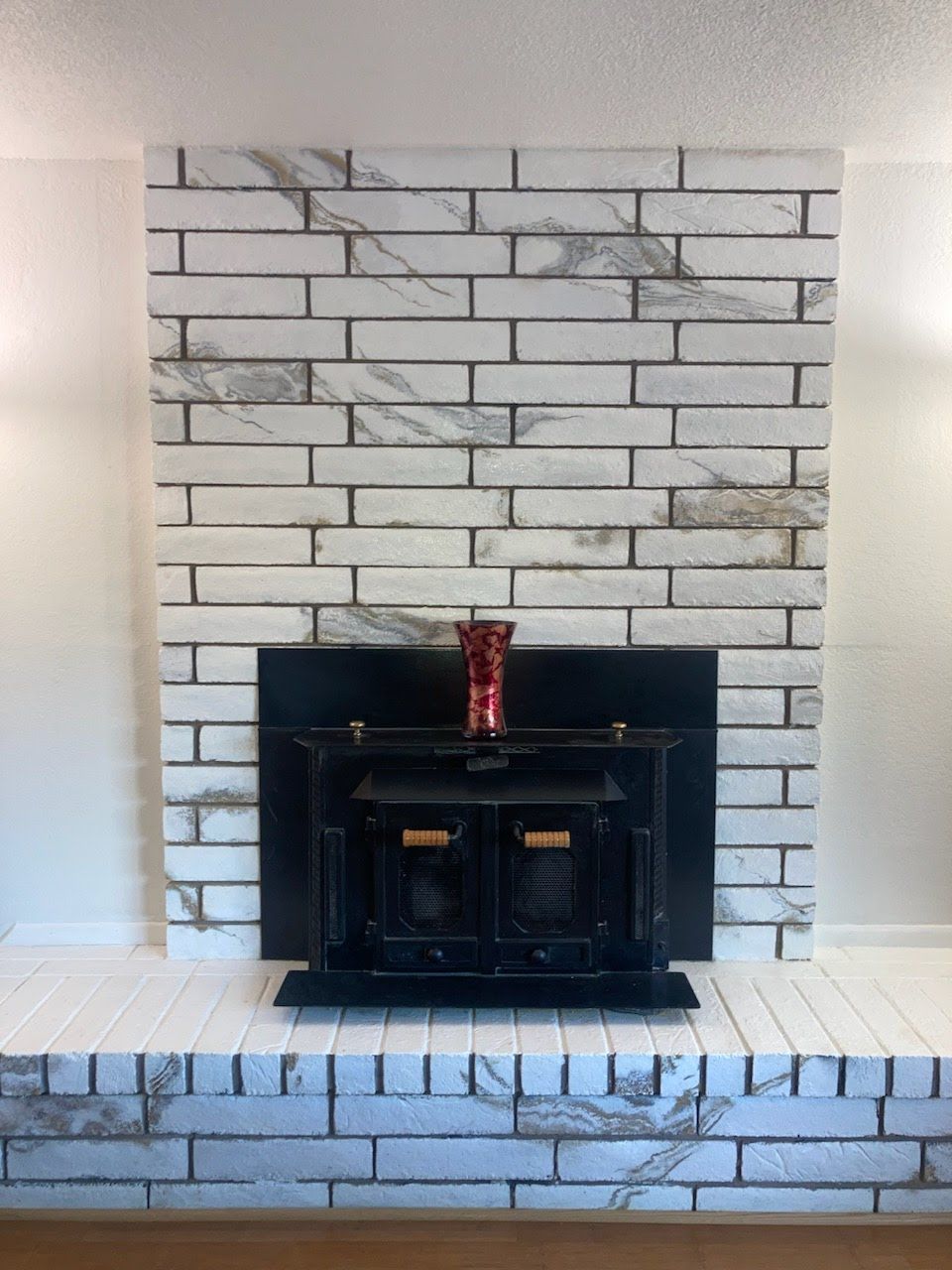 A white brick fireplace with a black screen