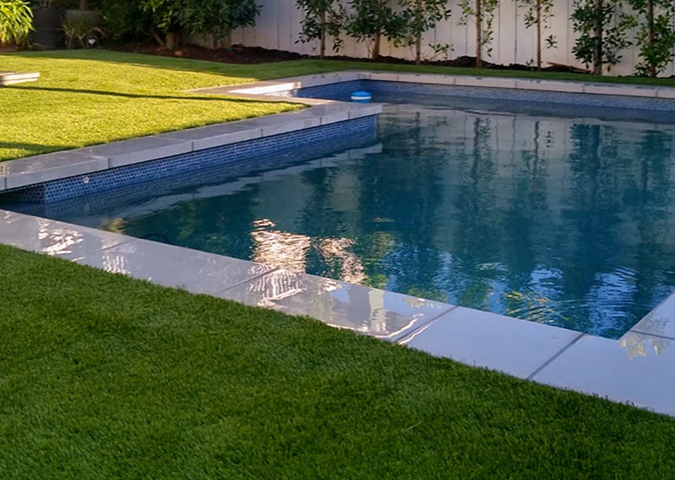 A backyard with a swimming pool and a grill