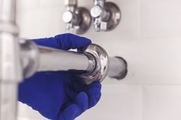 A plumber is fixing a pipe in a bathroom.