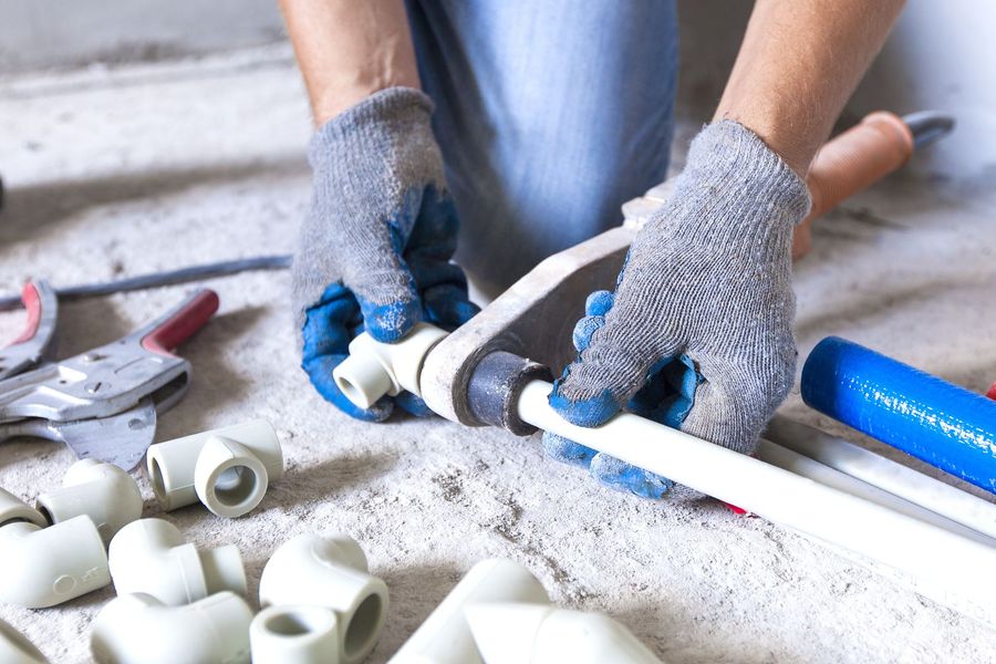 A plumber is working on a pipe on the floor.