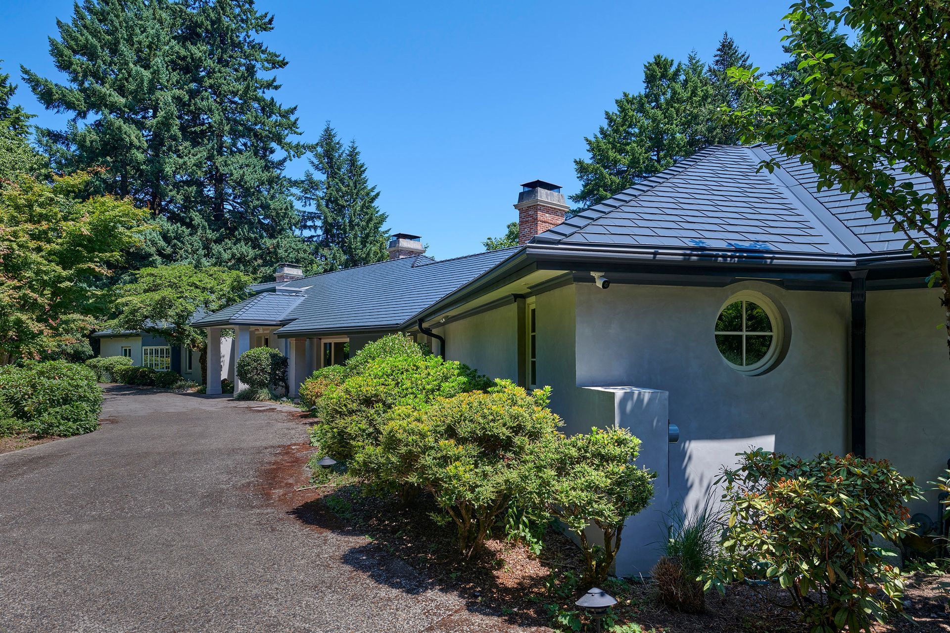 Ground-level front entry view of a Dunthorpe home with a Deep Charcoal Interlock Slate aluminum roof. The elegant metal roof enhances the estate’s timeless appearance, providing lasting beauty and performance in Multnomah County’s rainy climate.