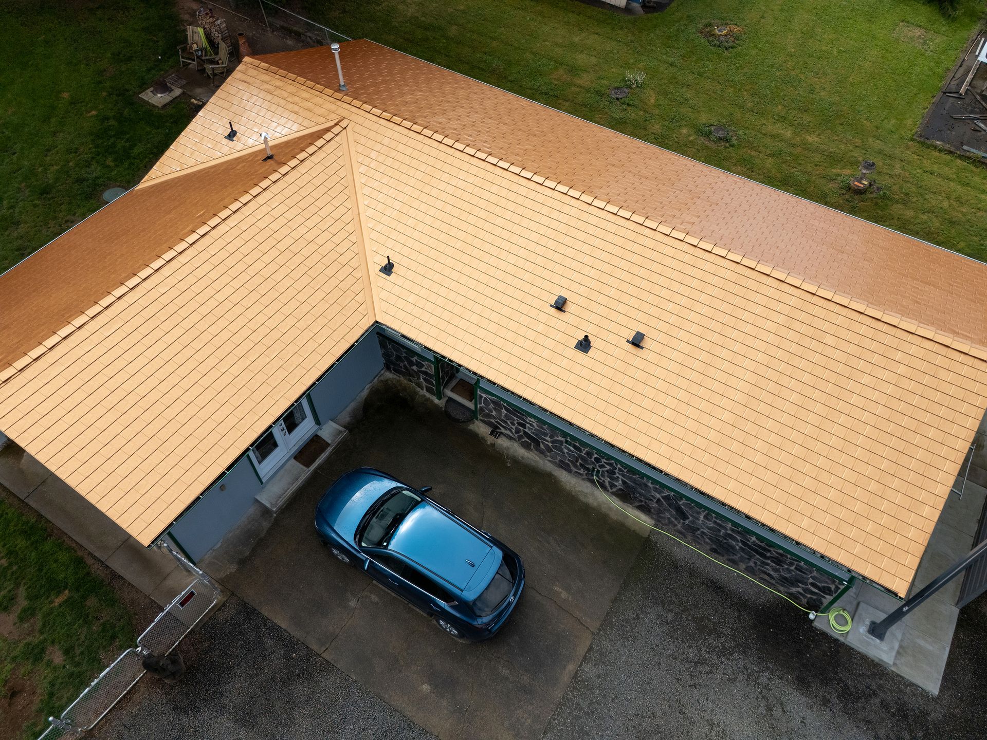 Top-down aerial perspective of a Copper Penny Interlock Slate Roof installed on a single-story home in the Lexington neighborhood of Castle Rock, WA. The precision-laid heavy-gauge aluminum panels offer fire resistance and longevity while complementing the home’s surrounding landscaping and stone facade.