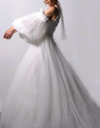 A woman is wearing a white wedding dress with long sleeves and a veil.