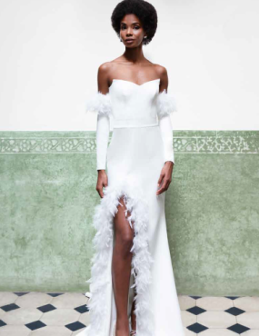 A woman in a white dress with feathers on the sleeves