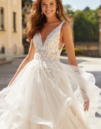 A woman is wearing a white wedding dress and smiling.