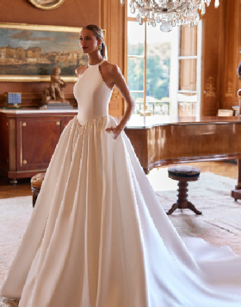 A woman in a white wedding dress is standing in front of a piano.