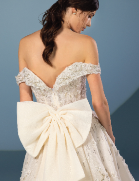 A woman is wearing a wedding dress with a large bow on the back.