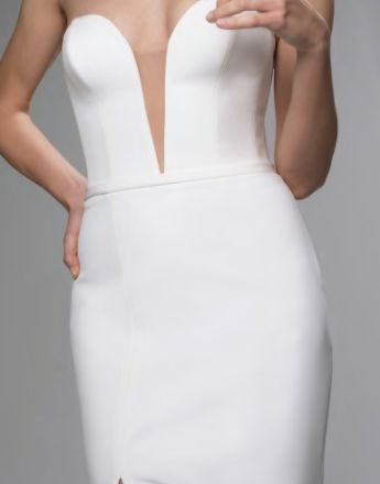 A woman is wearing a white dress with a plunging neckline.