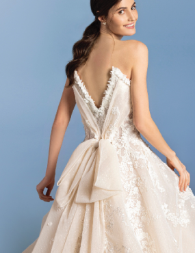 A woman is wearing a wedding dress with a bow on the back.