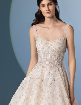 A woman in a white dress is standing in front of a blue background.