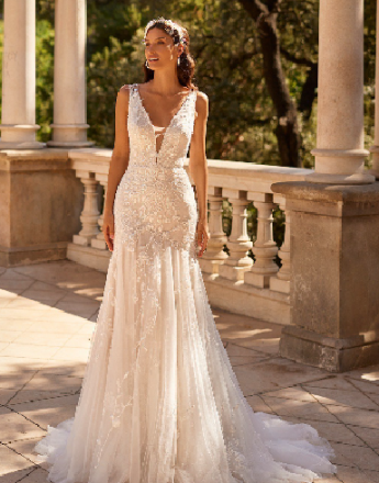 A woman in a white wedding dress is standing on a balcony.
