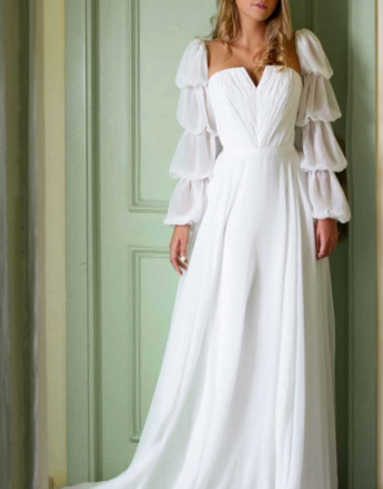 A woman in a white dress is standing in front of a door.