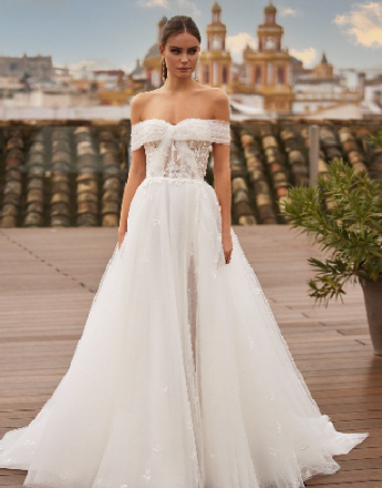 A woman in a white wedding dress is standing on a balcony.