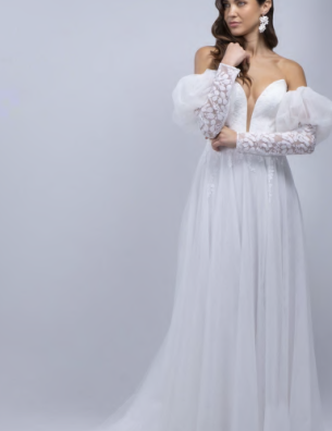 A woman is wearing a white wedding dress with long sleeves and a plunging neckline.