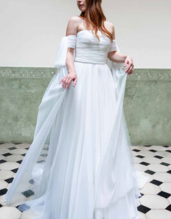 A woman in a white wedding dress is standing on a checkered floor.