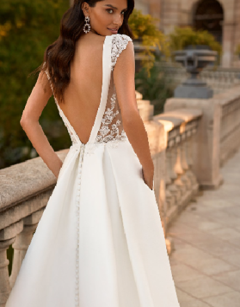 A woman in a white wedding dress is standing on a balcony.