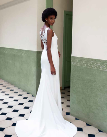 A woman in a white dress is standing in a hallway