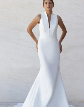 A woman in a white dress is standing in front of a wall