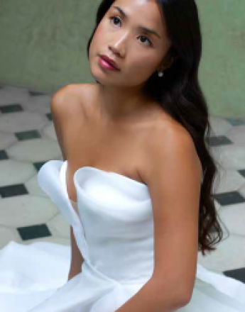 A woman in a white strapless dress is sitting on a tiled floor.