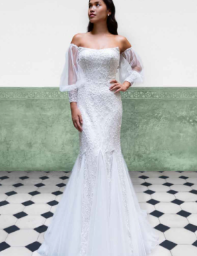 A woman in a white wedding dress is standing on a checkered floor.