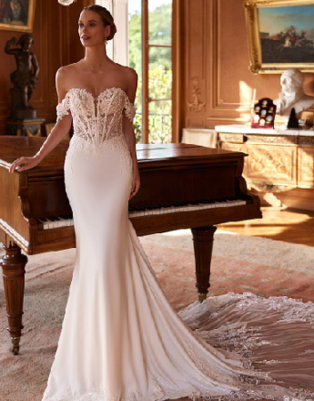 A woman in a white wedding dress is standing next to a piano.