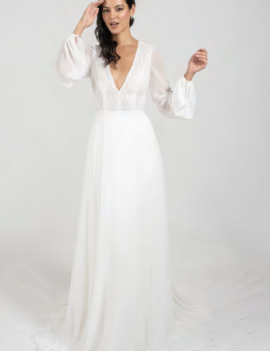 A woman is wearing a white dress with long sleeves and a plunging neckline.