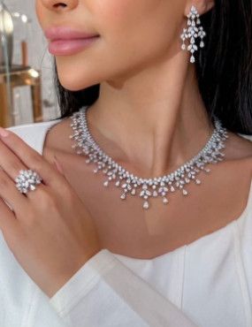 A woman is wearing a necklace , earrings , and ring.