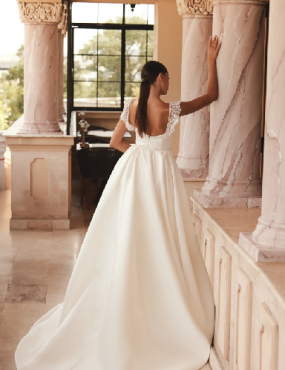 A woman in a wedding dress is leaning against a wall