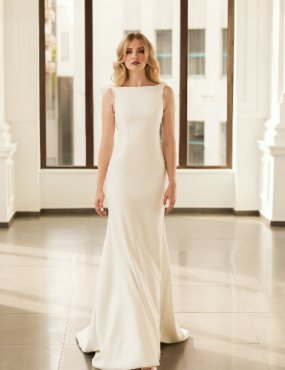 A woman in a white dress is standing in front of a window