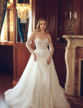 A woman in a wedding dress is standing in front of a fireplace.