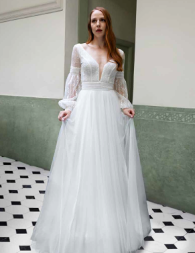 A woman in a white dress is standing in a hallway.