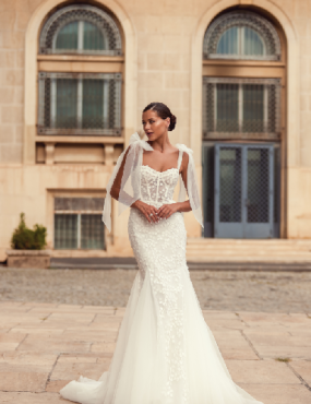 A woman in a wedding dress is standing in front of a building