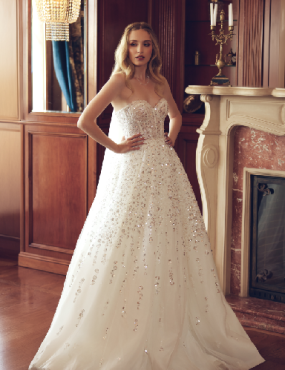 A woman in a wedding dress is standing in front of a fireplace