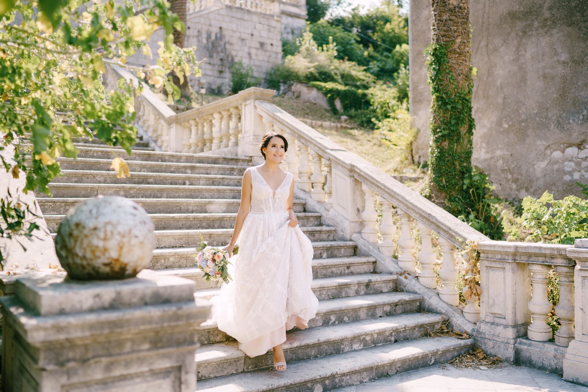 A bride in a wedding dress is walking down a set of stairs.