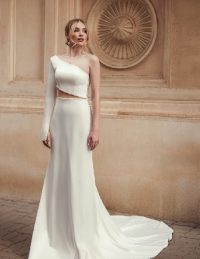 A woman in a white dress is standing in front of a building.