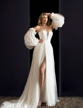 A woman in a white dress with puffed sleeves is standing in a doorway.