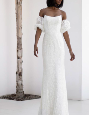 A woman in a white dress is standing next to a tree