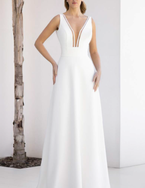 A woman in a white dress is standing next to a tree