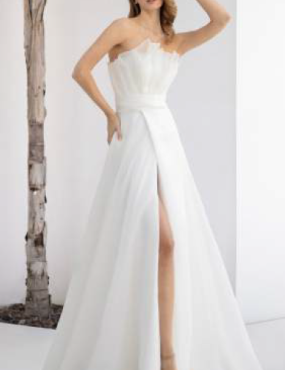 A woman is wearing a white wedding dress with a high slit.