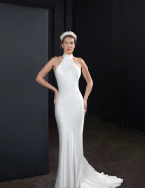 A woman in a white dress is standing in front of a black wall