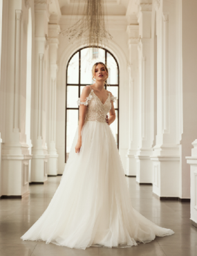 A woman in a white wedding dress is standing in a hallway.