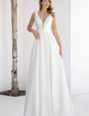 A woman in a white wedding dress is standing next to a tree.