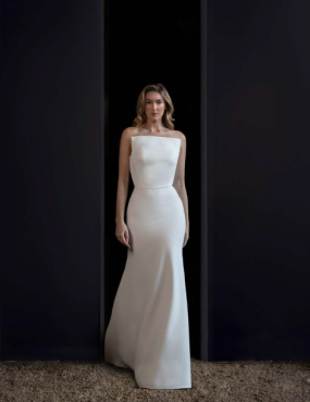 A woman in a white wedding dress is standing in a doorway.